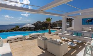 a patio with white furniture and a swimming pool at Fortan 5* villa in Mýkonos City
