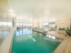 a large swimming pool with green water in a house at Spinneys Beachfront home, Indoor Pool UK-Vacations in Thorpeness