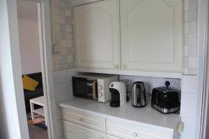 a kitchen with white cabinets and a microwave at Coolfin House - London Excel in London