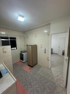 an empty room with a kitchen with a refrigerator at Apartamento em Praia Grande in Praia Grande