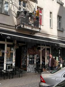 a man walking down a street in front of a store at Massagesessel, King-Sized Bed, Billardtisch, 2 Couches in Berlin