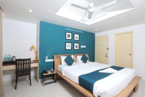 ein Schlafzimmer mit einer blauen Wand, einem Bett und einem Schreibtisch in der Unterkunft Naksha Tree Hotels, Honey Crest- Ramapuram in Chennai