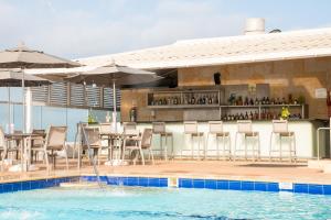 a bar with tables and chairs next to a swimming pool at Hotel Capilla del Mar in Cartagena de Indias