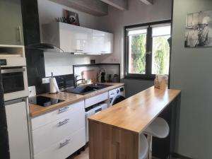 a kitchen with white cabinets and a wooden counter top at Au bord du vieux Moulin in Mérignac