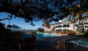 a resort with a swimming pool and tables and chairs at Hotel Pontal de Ubu in Anchieta