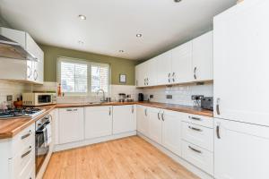 una cucina bianca con pavimenti in legno e armadi bianchi di Beautiful stay next to lakes and river a Nottingham