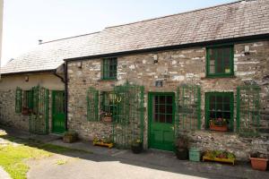 an old stone building with green doors and windows at Yr Hen Efail - Old Smithy in Tregaron
