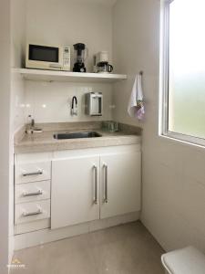 - une cuisine blanche avec évier et four micro-ondes dans l'établissement NossoApê Recanto: Casa de 3 quartos em Lima Duarte, à Lima Duarte