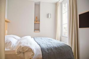 een witte slaapkamer met een bed en een raam bij Luxury and Design Perfect Apt Mouffetard 5th in Parijs