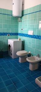サンタ・テレーザ・ガッルーラにあるLa Reggia Di Nausicaaの青いタイル張りのバスルーム(トイレ、洗濯機付)