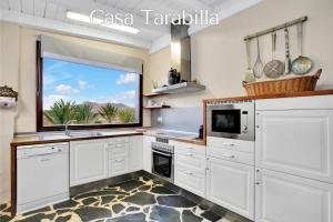 a kitchen with white cabinets and a large window at Casa Pilar, Aurora y Tarabilla en Finca Ecológica in Teguitar