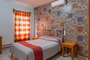 1 dormitorio con cama y pared de azulejos en Hotel Posada el Cid, en Oaxaca City