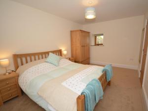een slaapkamer met een groot bed met een houten hoofdeinde bij 2 Bed in Bideford 32240 in Parkham