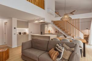 sala de estar con sofá, cocina y escalera en Marconia Boutique Residence, en L'Estartit