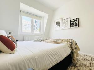 a white bedroom with a large bed and a window at 2 Bed Apartment next to Finsbury Park Station! (C) in London