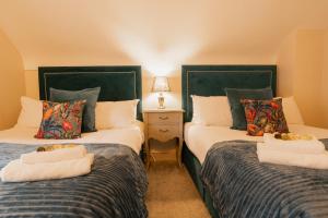 Duas camas individuais num quarto com um candeeiro sobre uma mesa em Newly renovated 3 bed Tarvin home -sleeps up to 11 em Tarvin