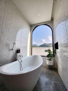 uma banheira branca na casa de banho com uma janela em Grandiva Khanom Pool Villa แกรนดิวา ขนอม พูลวิลล่า em Khanom