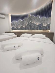 1 dormitorio con 2 camas, sábanas blancas y toallas en Grandiva Khanom Pool Villa แกรนดิวา ขนอม พูลวิลล่า, en Khanom