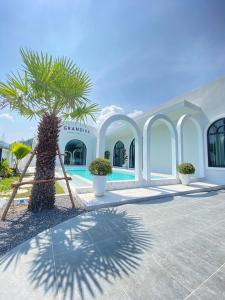 eine Palme vor einem Gebäude mit Pool in der Unterkunft Grandiva Khanom Pool Villa แกรนดิวา ขนอม พูลวิลล่า in Khanom