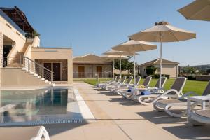 una fila de sillas y sombrillas junto a una piscina en Niriides Luxury Villas, en Methoni