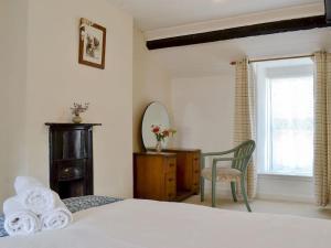 a bedroom with a bed and a chair and a window at Gerlan (no. 4, Station Rd) in Tregaron