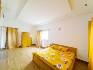 ein Schlafzimmer mit einem Bett mit einer gelben Bettdecke mit Blumen in der Unterkunft GM IMMO SARL in Cotonou