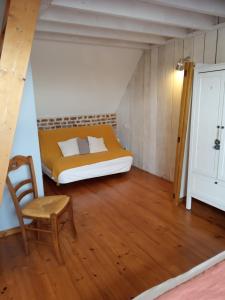 ein kleines Schlafzimmer mit einem Bett und einem Stuhl in der Unterkunft La grange d'Armand in Mentheville