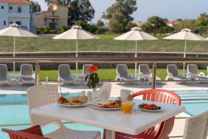 a white table with food on it next to a pool at Niriides Luxury Villas in Methoni