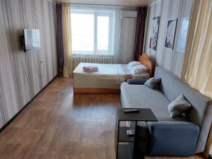 ein Wohnzimmer mit einem Sofa und einem Bett in der Unterkunft Комфортная квартира с удобным расположением in Līsakovsk