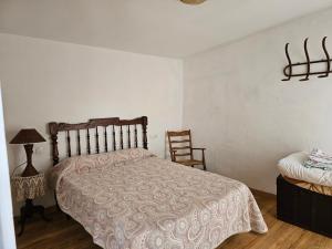 um quarto com uma cama e uma cadeira em CASA DEL LLAVADOR Vall de Guadalest em Benifató