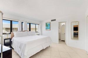 a white bedroom with a large bed and a bathroom at Overlooking Marina/Ocean view & FREE GOLF CART in Key Largo