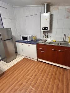 una pequeña cocina con fregadero y microondas en Casa familiar, en Temuco