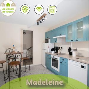 cocina con armarios azules, mesa y sillas en Madeleine - Maison proche des Arènes en Arlés