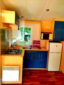 eine Küche mit blauen Schränken und einem weißen Kühlschrank in der Unterkunft Bungalow de 2 chambres avec piscine partagee a Saint Cheron in Saint-Chéron