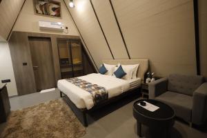 een slaapkamer met een bed, een bank en een stoel bij Vindhyachal Resort in Kevadia