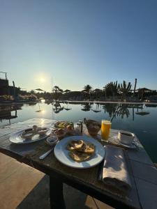 a table with plates of food on it next to a pool at Fellah Hotel in Marrakesh