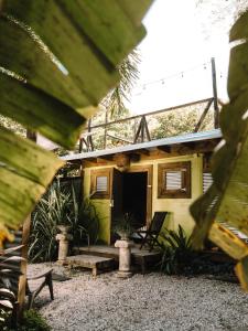 a small yellow house with a porch and a chair at Hacienda Tres Casitas in Cabo Rojo