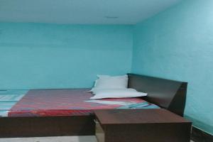 a bed in a room with a blue wall at SPOT ON Pushpanjali Guest House in Patna