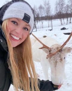 a woman is smiling next to a cow in the snow at Ringstad Resort in Bø