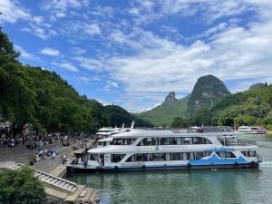 a cruise ship in the water with mountains in the background at Guilin Village Creek Inn in Guilin