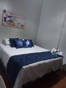 uma cama com almofadas azuis e brancas num quarto em Terra Encantada Pousada Fernando de Noronha em Fernando de Noronha