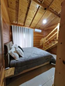 Un dormitorio con una cama en una cabaña de madera. en Recanto Pôr do Sol, en Urubici