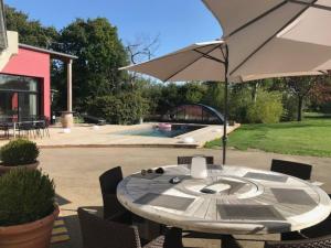 a table with an umbrella next to a pool at Villa de 4 chambres avec piscine privee terrasse et wifi a Plouigneau in Plouigneau