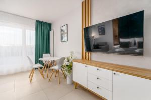 a living room with a large tv on the wall at Aquamarina Prima Holiday Studios by the BEACH by Noclegi Renters in Międzyzdroje