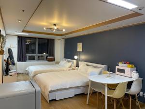 a hotel room with two beds and a table and a kitchen at Serein_HongDae in Seoul