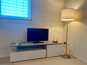 Ein Wohnzimmer mit einem Fernseher auf einem Schreibtisch mit einer Lampe in der Unterkunft Residenza Sant'Agostino in Altavilla Vicentina