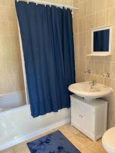 Gresham House - London Excel في لندن: حمام مع ستارة دش زرقاء ومغسلة