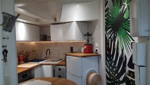 una pequeña cocina con armarios blancos y fregadero en Chambre cosy dans petit loft, en París