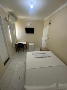 a room with two beds and a table and a tv at Hotel Rio Center in Juazeiro