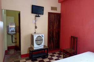 Zimmer mit einem Bett und einem TV an der Wand in der Unterkunft OYO Prabha Guest House in Robertsganj